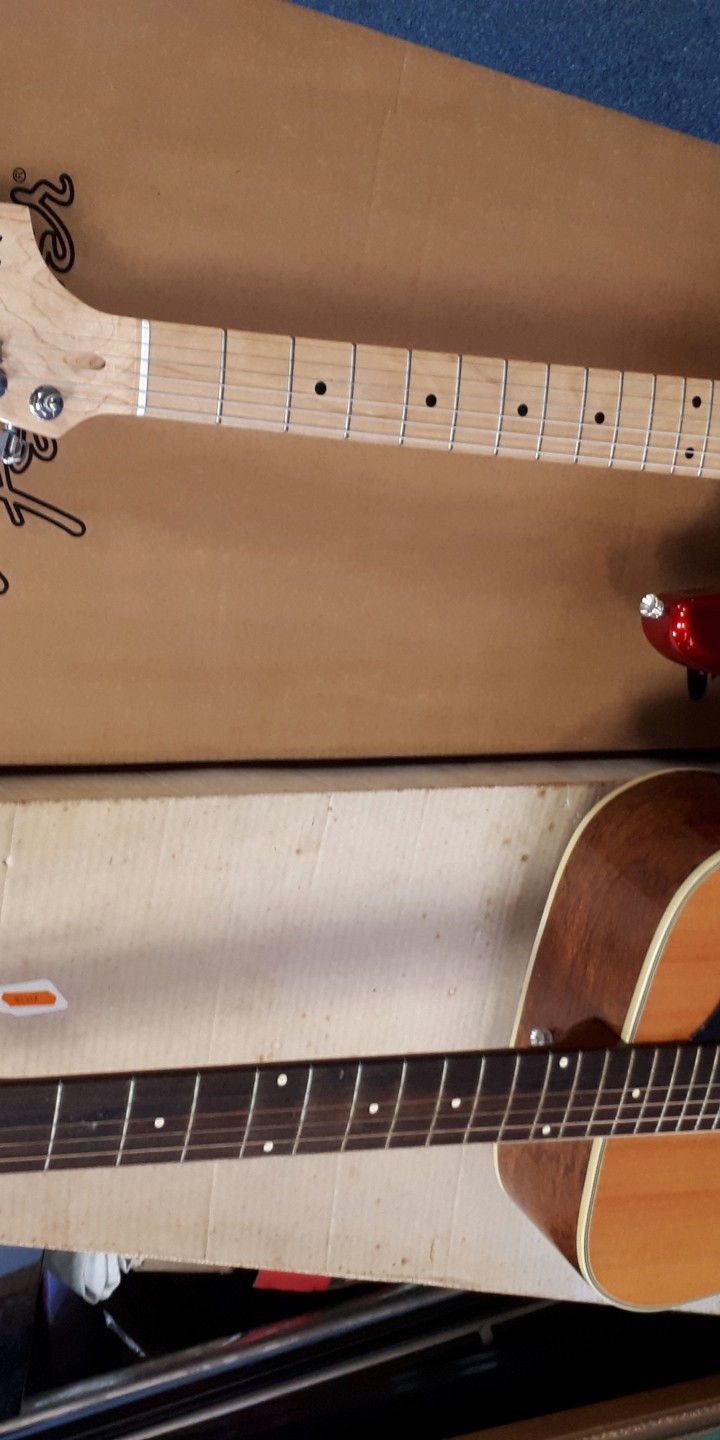 An Eko Acoustic Guitar And A Fender Squier Strat