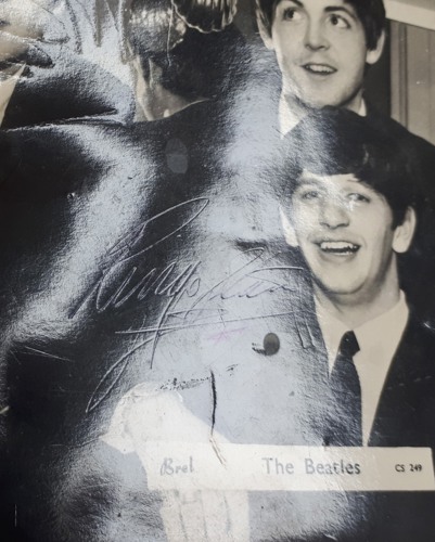 Ringo Starr's signature is cloaked by the group's dark suits yet visible due to the impression of the pen.