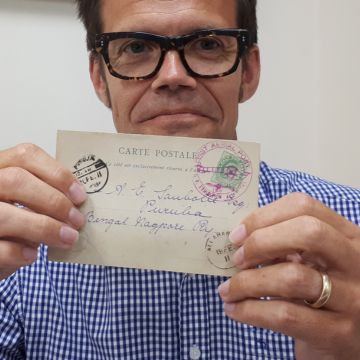 Richard Winterton Auctioneers’ philately specialist Phil Ives with the postcard sent on the world’s first official airmail flight.